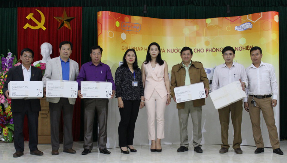 Đồng chí Hoàng Thị Chung cùng đại diện Công ty cổ phần y tế Quang Minh tặng máy xét nghiệm cho một số Bệnh viện