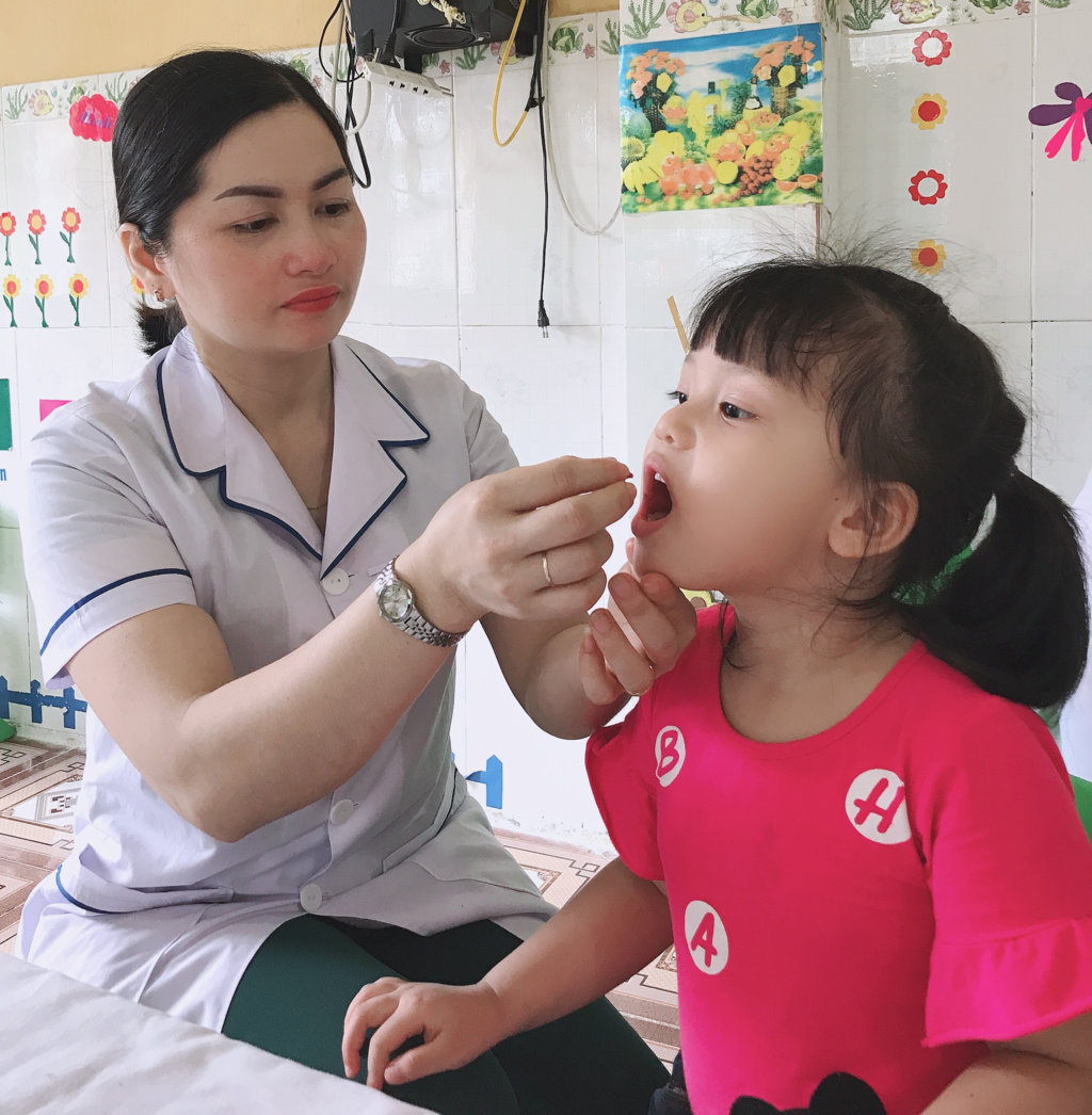 Cán bộ Trạm Y tế phường Minh Khai cho trẻ uống Vitamin A tại Trường Mầm non