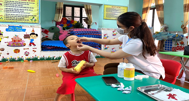 Cán bộ y tế bổ sung Vitamin A cho trẻ tại trường Mầm non Hoa Hồng
