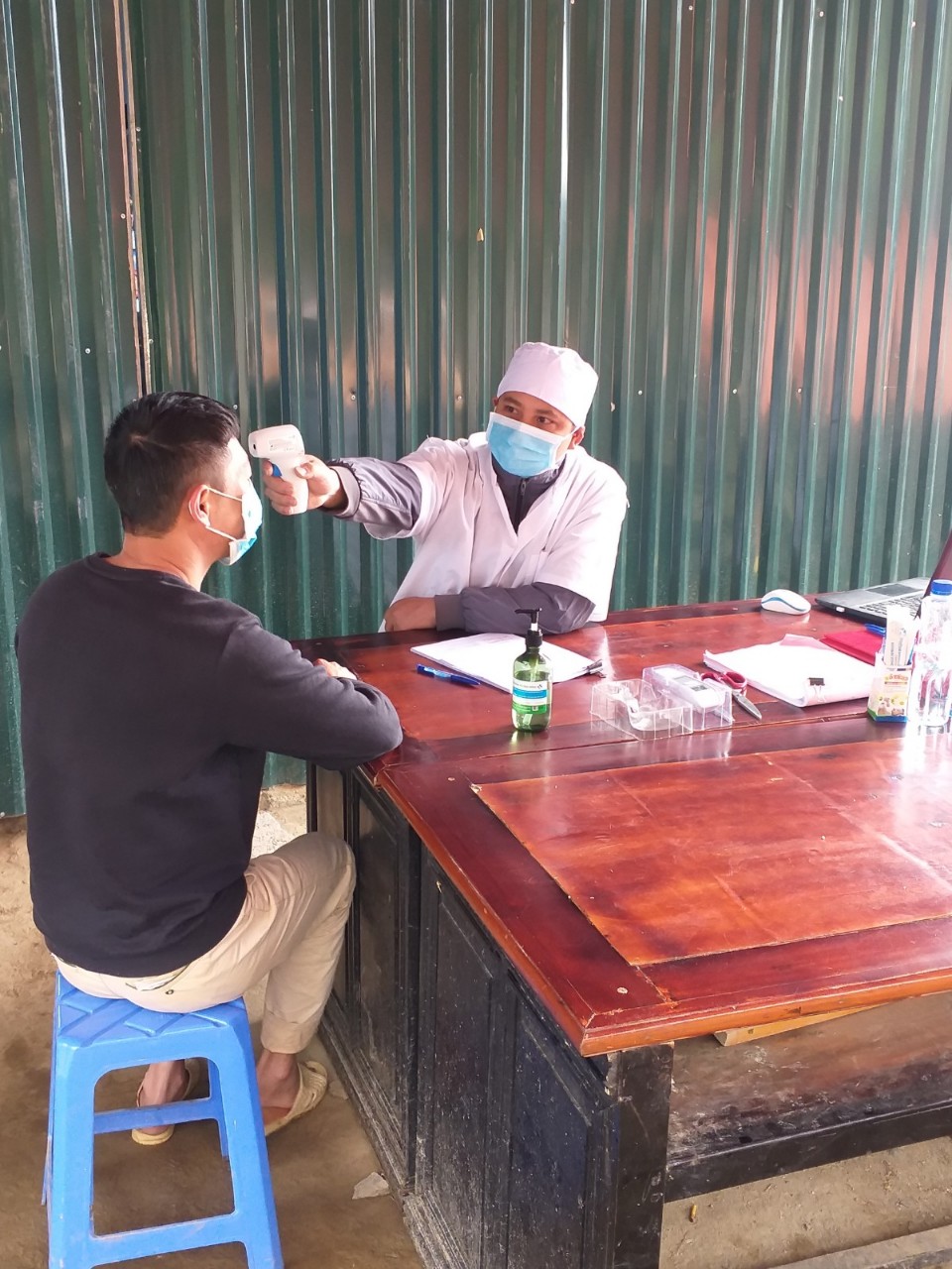 Y sĩ Nguyễn Hữu Tình kiểm tra sức khỏe và đo thân nhiệt cho người dân  tại chốt kiểm dịch y tế Nàn Ma