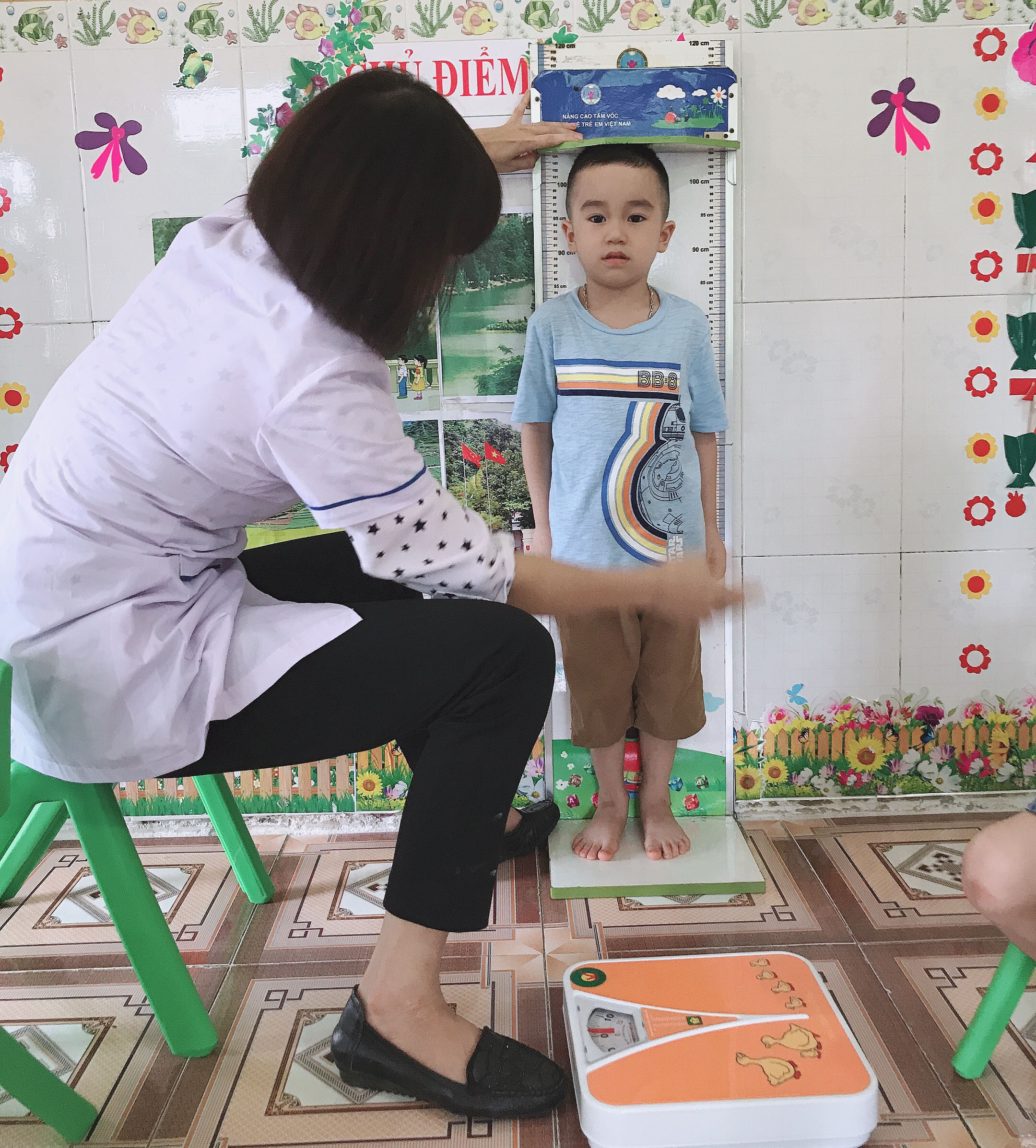 Cán bộ Trạm Y tế phường Minh Khai cân, đo chiều cao cho trẻ 